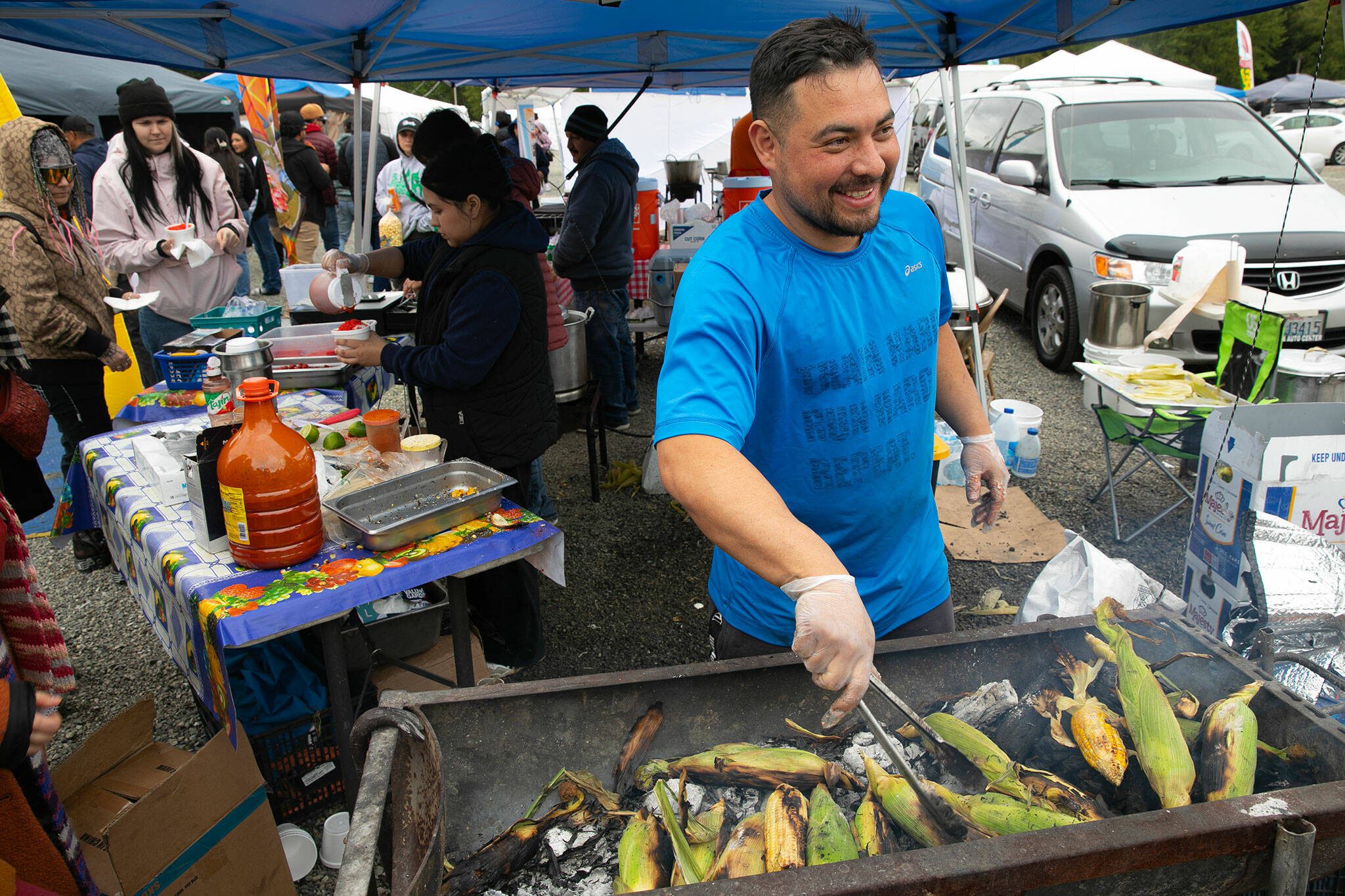 Joel Jacinto of Seattle Sweetcorn works over an open pit while charring corn to make elotes and esquites at the Hidden Gems Weekend Market on Sunday, April 28, 2024, at Boom City in Tulalip, Washington. (Ryan Berry / The Herald)