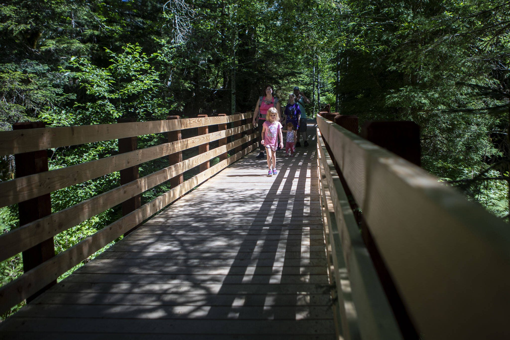 People walk along a bridge at the Big Four Ice Caves hike along the Mountain Loop Highway in Snohomish County, Washington on Wednesday, July 19, 2023. (Annie Barker / The Herald)