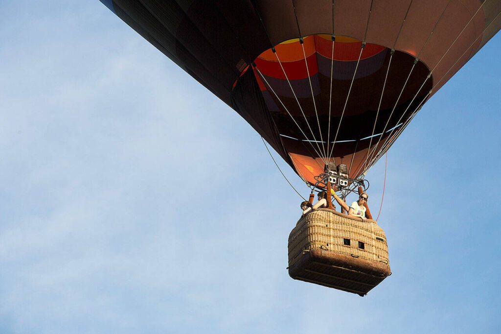 Jill Van Rawley peers out from the basket as pilot Jay Woodward, owner of Balloon Depot, takes riders on a hot air balloon trips over Snohomish Valley on Monday, June 18, 2018 in Snohomish, Wa. The hot air balloon ride was a first for Van Rawley, of Philadelphia, Pa. (Andy Bronson / The Herald)
