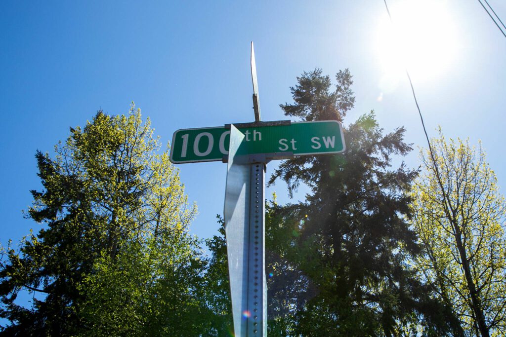 Trees on the lot of a proposed park rise above a street sign at the intersection of Holly Drive and 100th Street SW on Thursday, May 2, 2024, in Everett, Washington. (Ryan Berry / The Herald)
