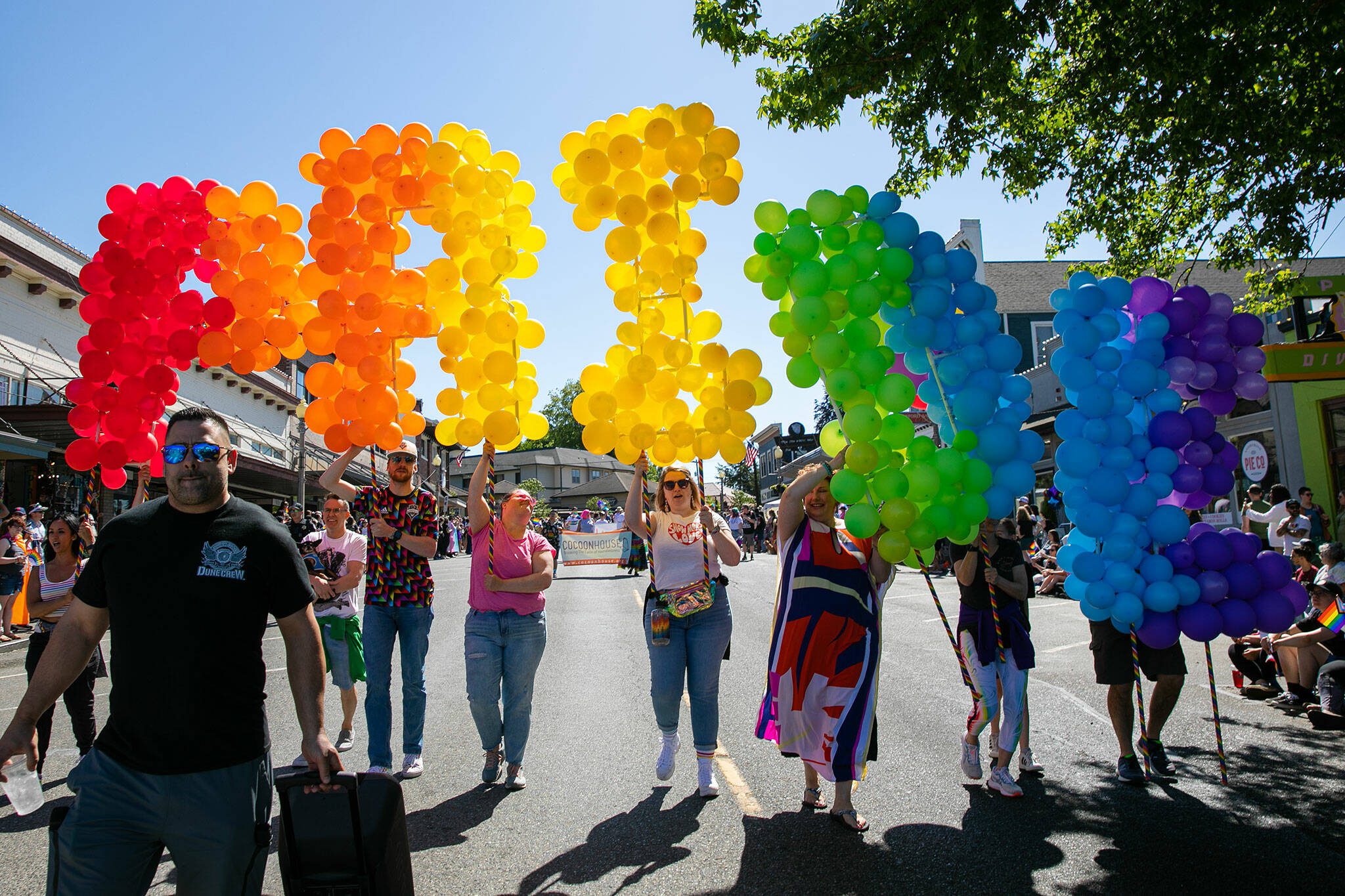 People begin parading down First Street with a giant balloon “PRIDE” during Snohomish’s inaugural Pride celebration on Saturday, June 3, 2023, in downtown Snohomish, Washington. (Ryan Berry / The Herald)