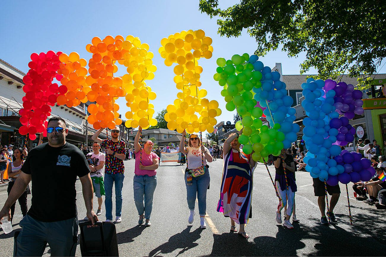 People parading marching down First Street with a giant balloon “PRIDE” during Snohomish’s inaugural Pride celebration on Saturday, June 3, 2023, in downtown Snohomish, Washington. (Ryan Berry / The Herald)