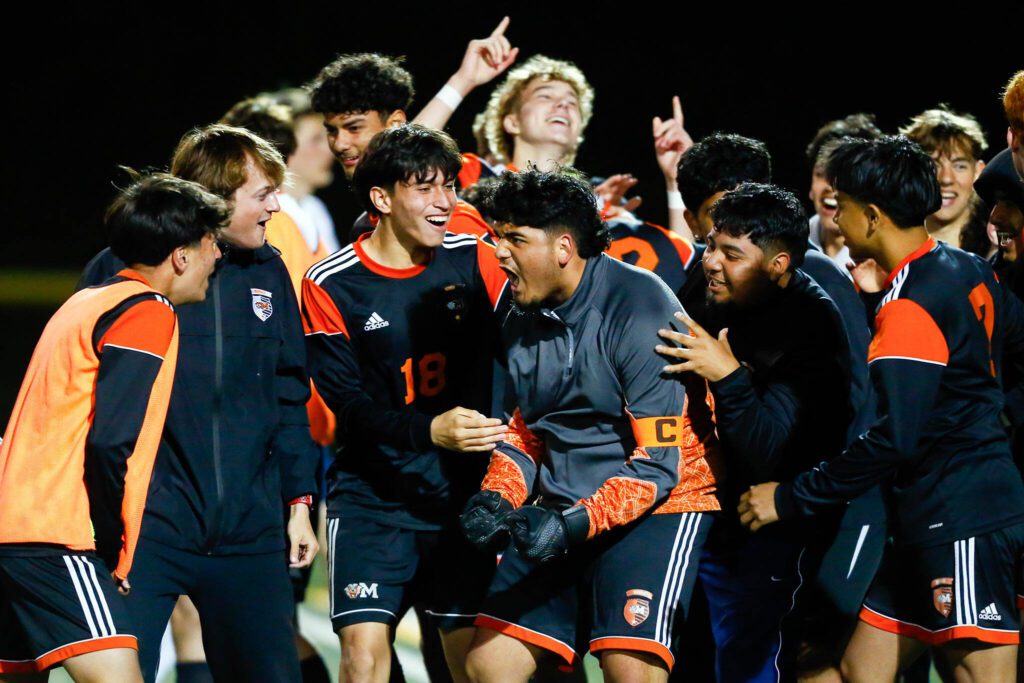 The Monroe Bearcats swarm goalkeeper Brandon Alonso after he helped the team seal a victory during a 3A District soccer match against Everett that went to PKs on Thursday, May 2, 2024, at Monroe High School in Monroe, Washington. (Ryan Berry / The Herald)
