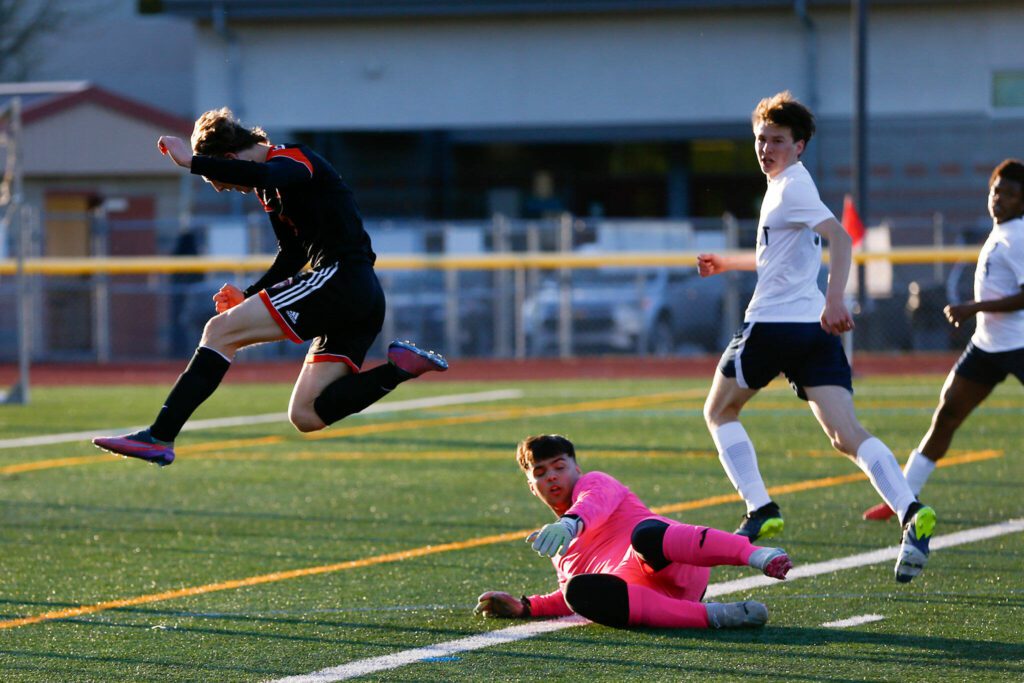 Monroe’s Tanner Summers jumps over Everett goalkeeper Tristan Slater after a save by Slater during a 3A District soccer match on Thursday, May 2, 2024, at Monroe High School in Monroe, Washington. (Ryan Berry / The Herald)
