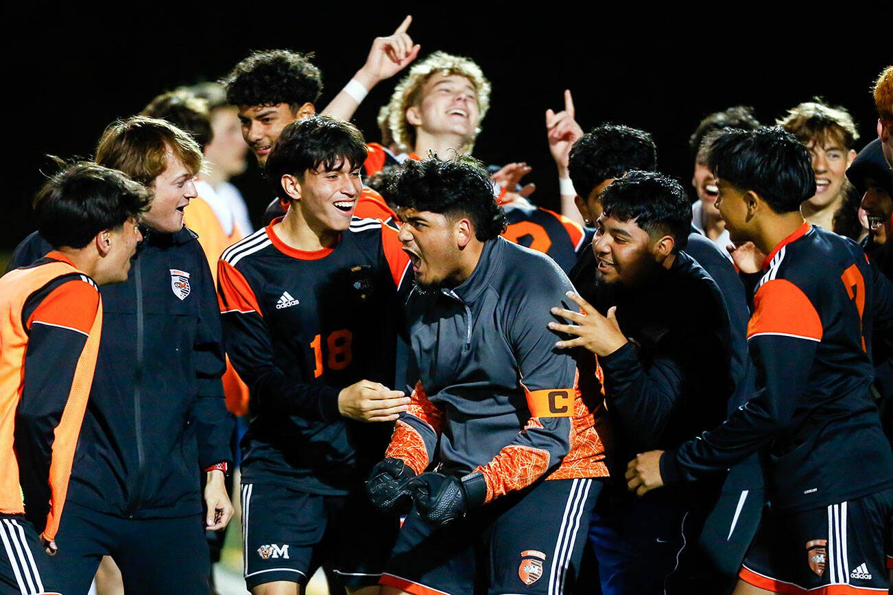 The Monroe Bearcats swarm goalkeeper Brandon Alonso after he helped the team seal a victory during a 3A District soccer match against Everett that went to PKs on Thursday, May 2, 2024, at Monroe High School in Monroe, Washington. (Ryan Berry / The Herald)