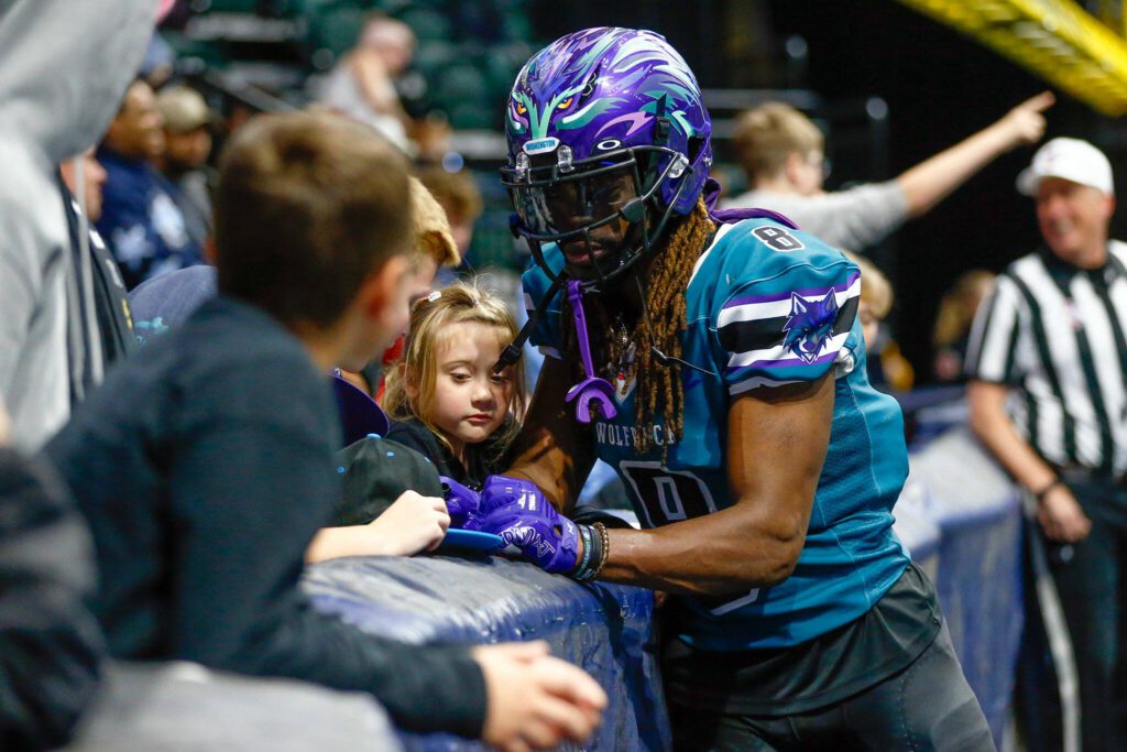 Wideout Vincent Wilkerson signs a hat for a young fan before taking a kick return during the Washington Wolfpack’s inaugural home opener against Billings on Sunday, May 5, 2024, a Angel of the Winds Arena in Everett, Washington. (Ryan Berry / The Herald)
