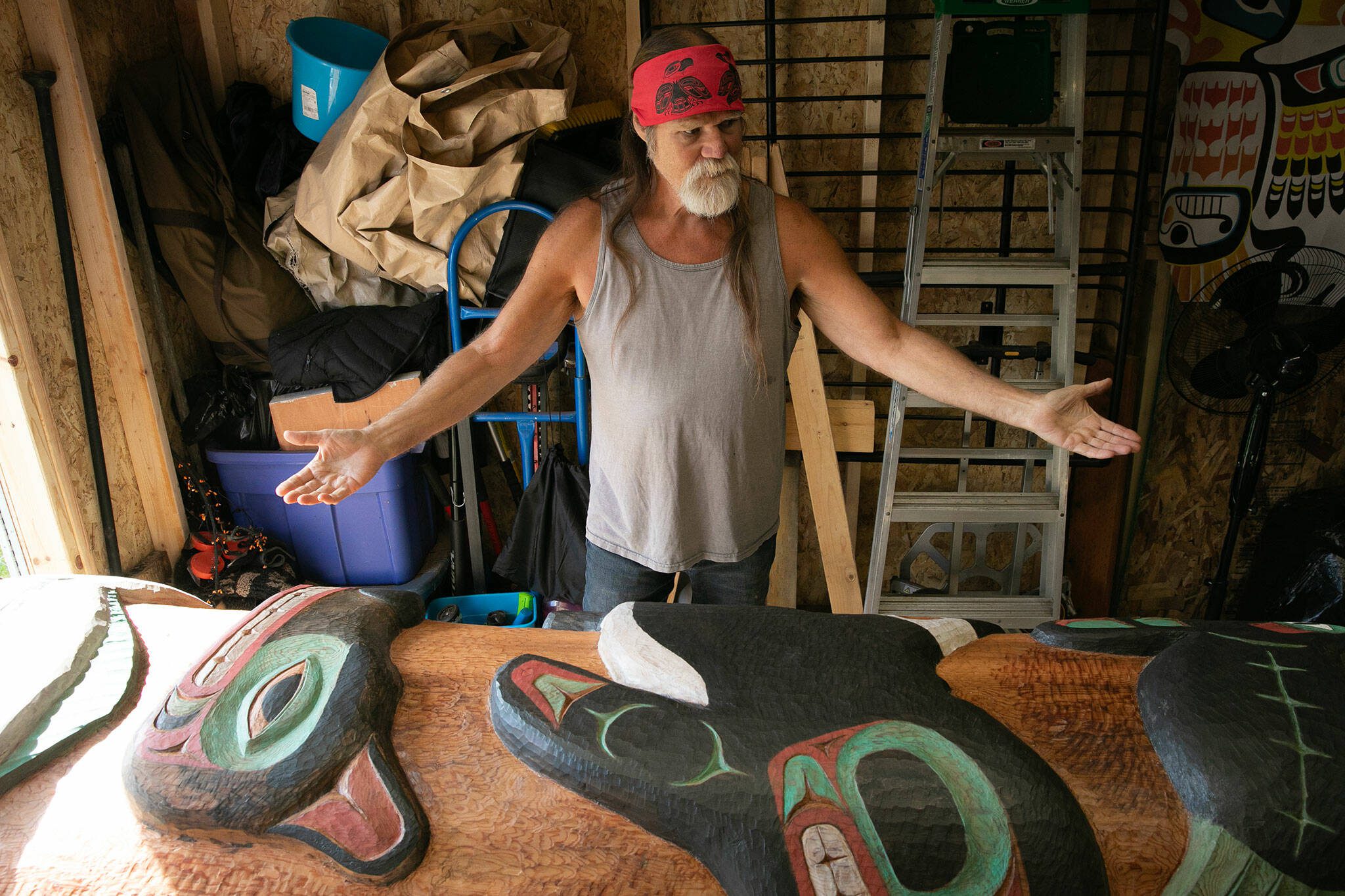 Tlingit Artist Fred Fulmer stands over a completed information totem pole inside his workshop on Wednesday, May 8, 2024, at his home in Everett, Washington. The pole will be packed up in the coming days and shipped to Petersburg, Alaska. (Ryan Berry / The Herald)