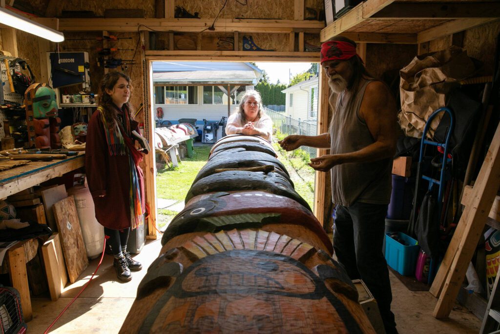 Fred Fulmer, right, and wife of 46 years Ivy Fulmer, center, talk with The Herald about Fred’s totem pole on Wednesday, May 8, 2024, at his home in Everett, Washington. (Ryan Berry / The Herald)
