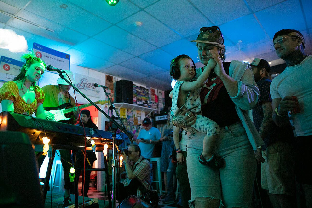 A child gets some assistance dancing during Narrow Tarot’s set on the opening night of Fisherman’s Village on Thursday, May 18, 2023, at Lucky Dime in downtown Everett, Washington. (Ryan Berry / The Herald)