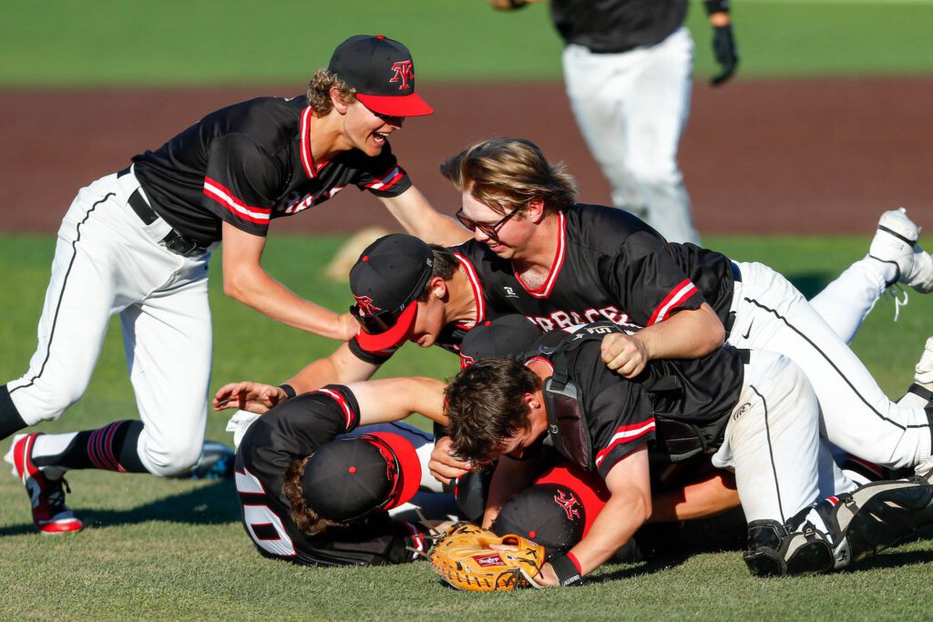 Mountlake Terrace teammates dogpile on pitcher Owen Meek after his complete game victory against Edmonds-Woodway in the Class 3A District 1 baseball championship Saturday, May 11, 2024, at Funko Field in Everett, Washington. (Ryan Berry / The Herald)
