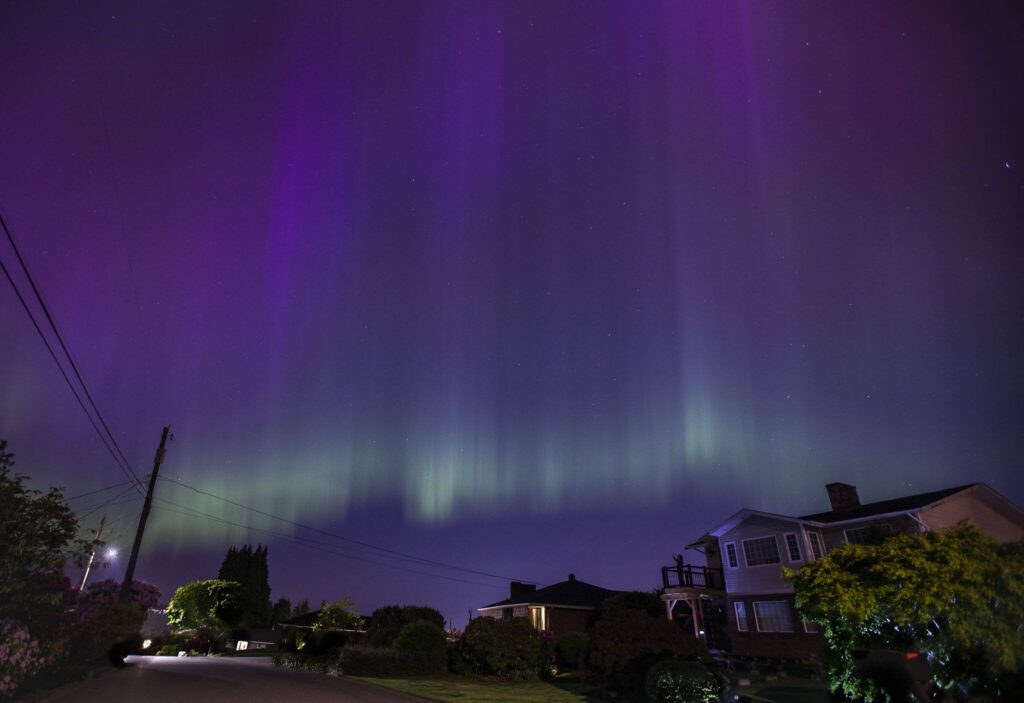 A person takes photos of the aurora borealis from their deck near Howarth Park on Friday, May 10, 2024 in Everett, Washington. (Olivia Vanni / The Herald)
