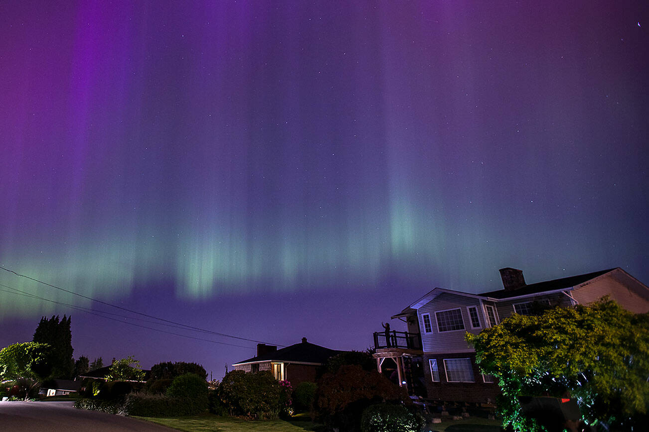 A person takes photos of the aurora borealis from their deck near Howarth Park on Friday, May 10, 2024 in Everett, Washington. (Olivia Vanni / The Herald)