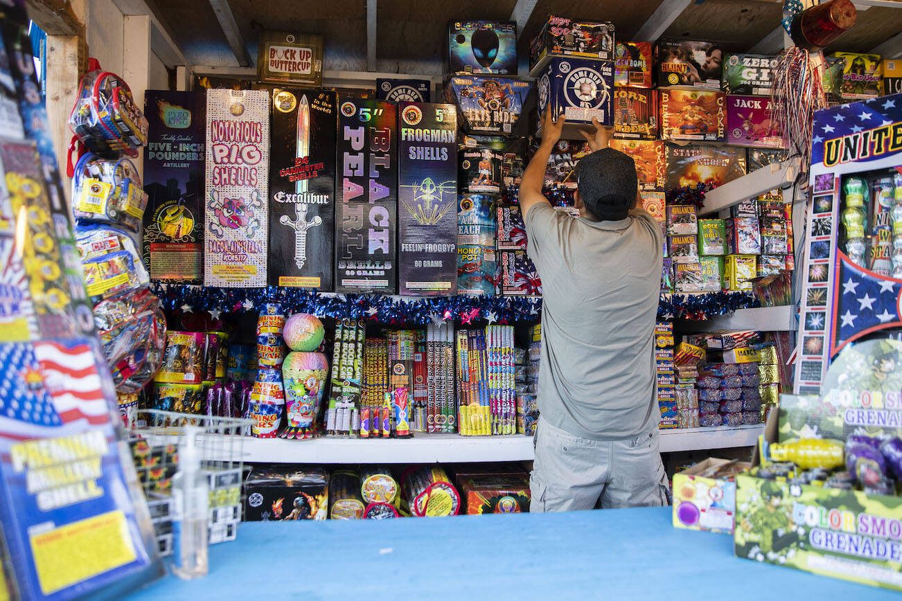 Brandon Moses pulls down boxes of fireworks for a customer at Monty Hall Fireworks at Boom City on Thursday, June 30, 2022 in Tulalip, Washington. (Olivia Vanni / The Herald)