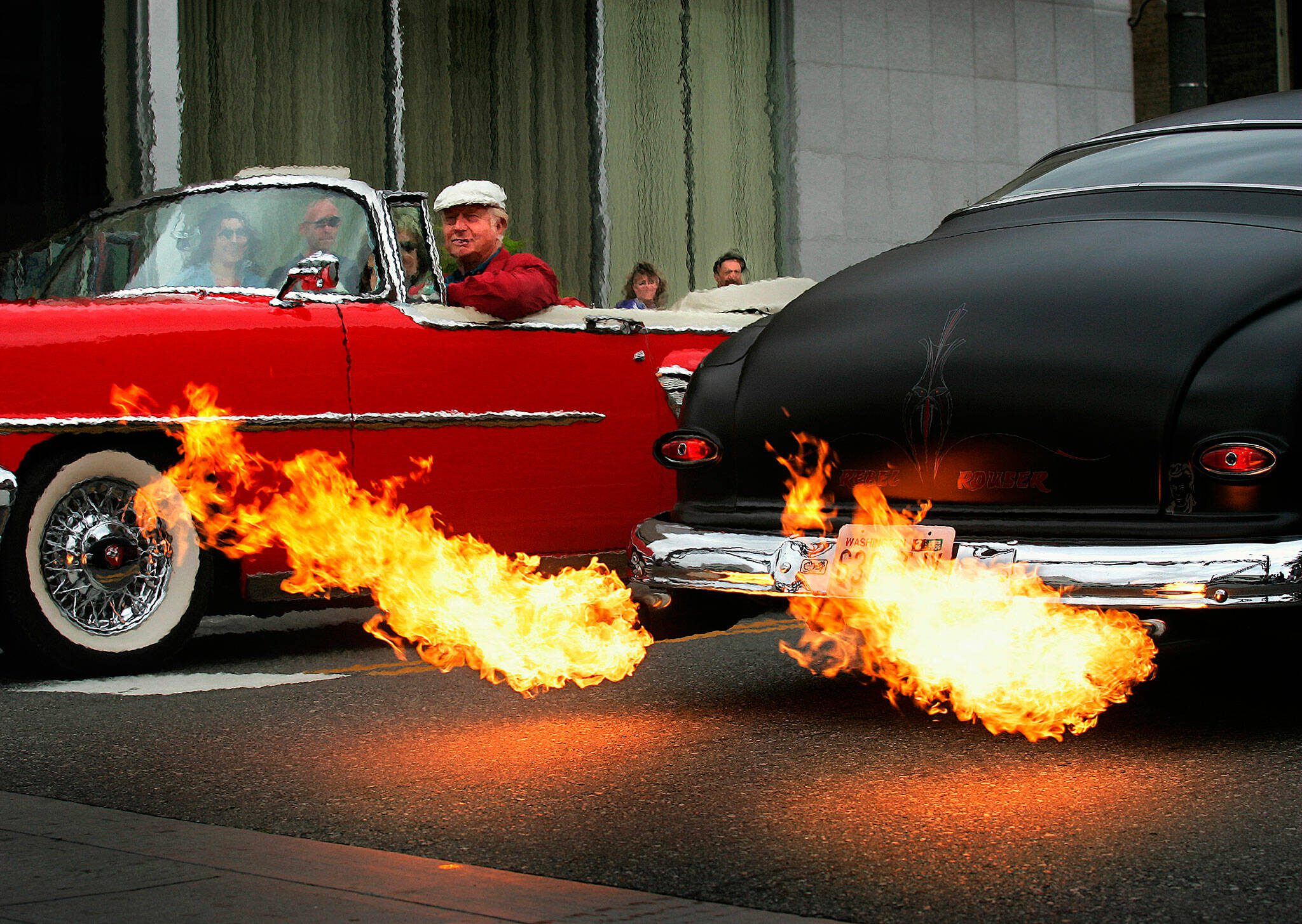 To the amazement of onlookers, flames shoot out the exhaust pipes on Les Sanders’ black 1950 Mercury Coupe as he drives up and down Colby Avenue with many others in classic and custom automobiles during one of the many popular Cruzin’ to Colby events held each summer in Everett. (Dan Bates / The Herald)