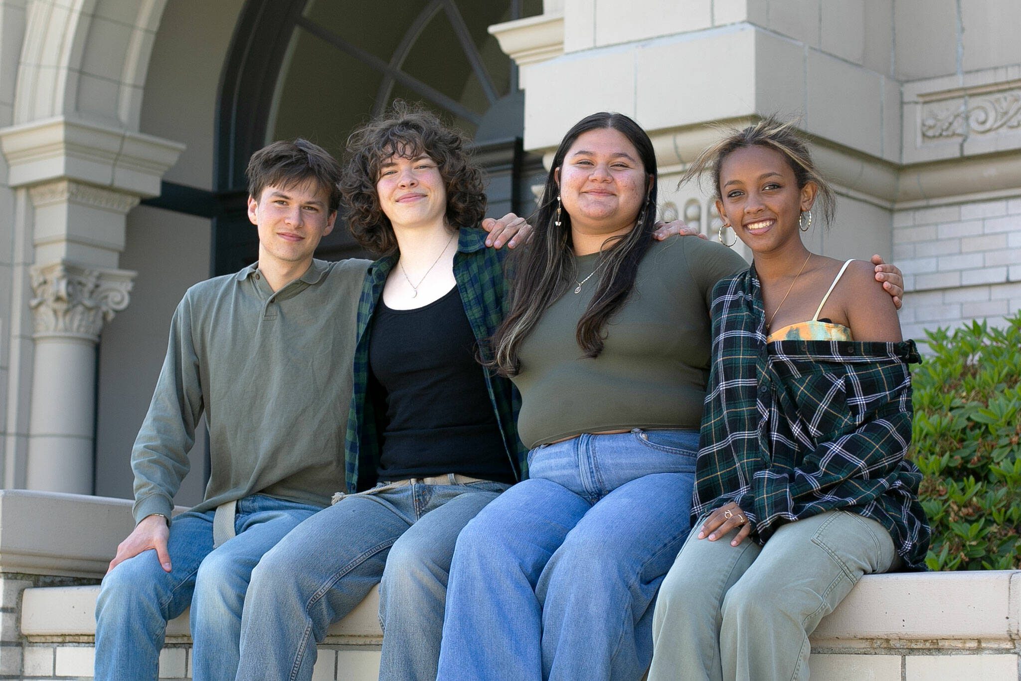 Everett High seniors, from left, Avery Thompson, Lanie Thompson, Melissa Rosales-Alfaro and Saron Mulugeta sit together in front of their school on Monday, May 20, 2024, in Everett, Washington. The group have called to question their district’s policy that does not permit graduates to decorate their mortarboards or graduation clothing. (Ryan Berry / The Herald)