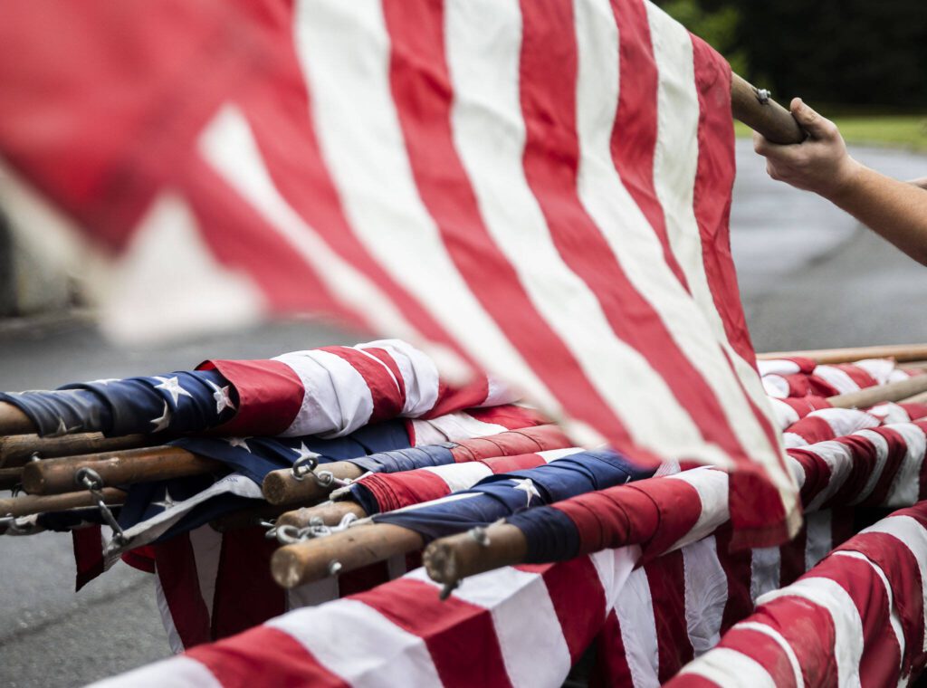 Flags hang off the back of a cart while maintenance crew set up for Memorial Day at Floral Hills Cemetery on Friday, May 24, 2024 in Lynnwood, Washington. (Olivia Vanni / The Herald)
