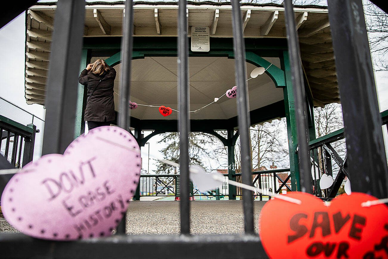 People hang up hearts with messages about saving the Clark Park gazebo during a “heart bomb” event hosted by Historic Everett on Saturday, Feb. 17, 2024 in Everett, Washington. (Olivia Vanni / The Herald)