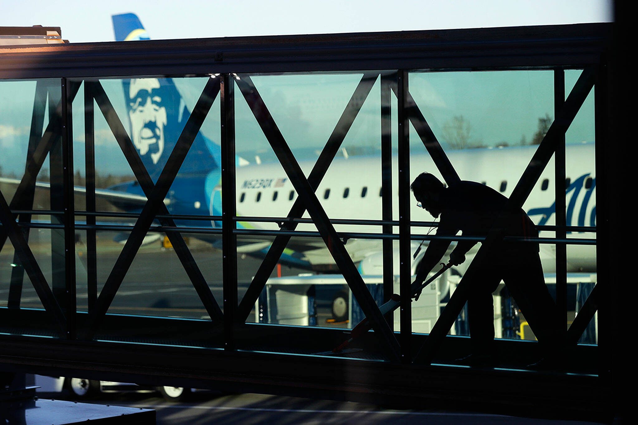 A worker cleans a jet bridge at Paine Field in Everett, before passengers board an Alaska Airlines flight in March of 2019. (Ted S. Warren / Associated Press file photo)