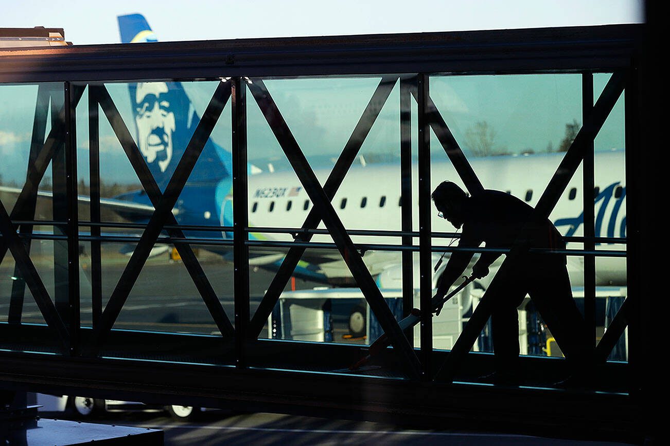 FILE - A worker cleans a jet bridge at Paine Field in Everett, Wash., before passengers board an Alaska Airlines flight, March 4, 2019. Seattle-based Alaska Airlines owns Horizon Air. Three passengers sued Alaska Airlines on Thursday, Nov. 2, 2023, saying they suffered emotional distress from an incident last month in which an off-duty pilot, was accused of trying to shut down the engines of a flight from Washington state to San Francisco. (AP Photo/Ted S. Warren, File)