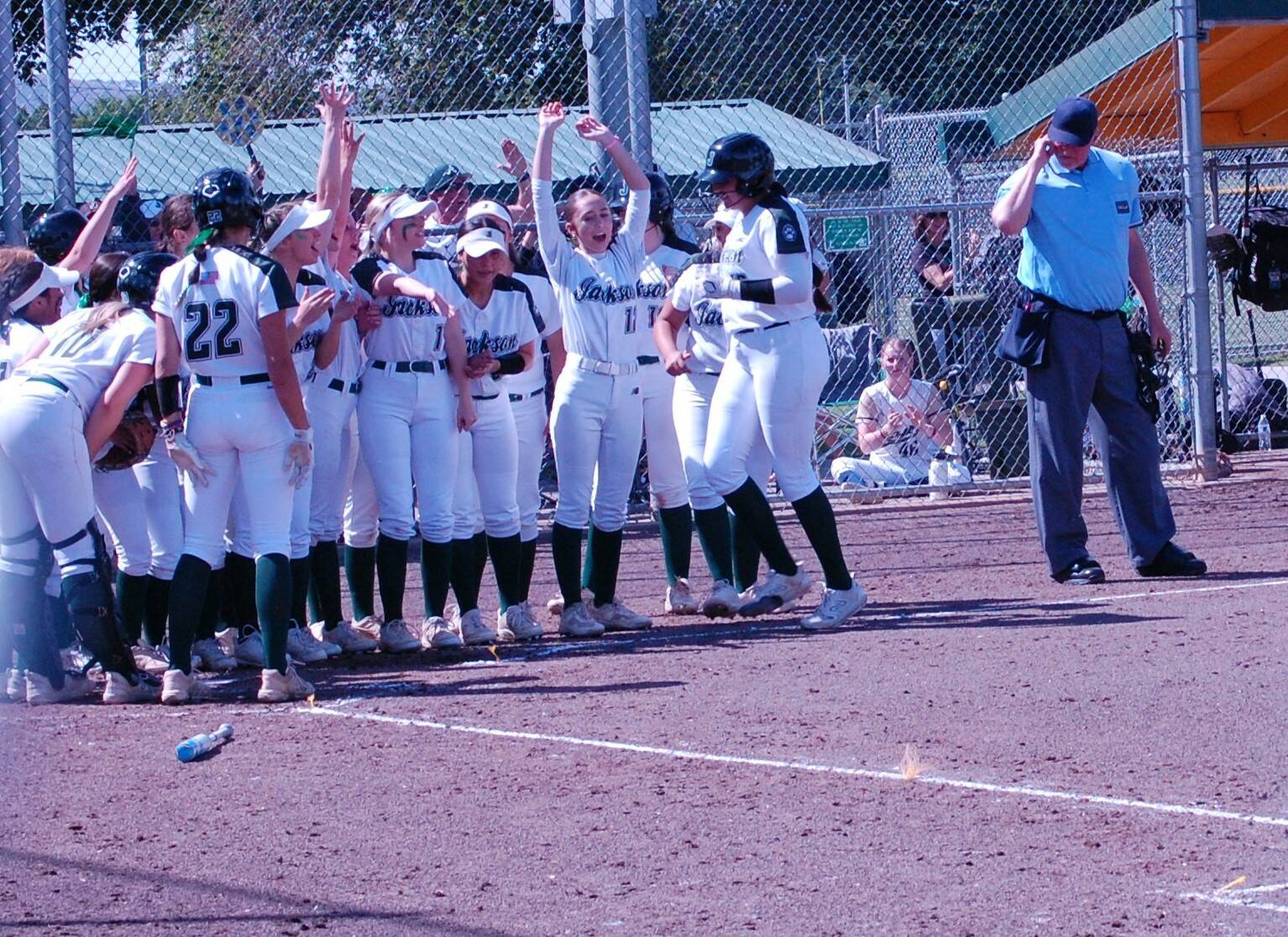 The Jackson softball team greets Yanina Sherwood after her sixth-inning, two-run homer put Jackson ahead 4-1 a Class 4A state playoff first-round game May 24 at Columbia Playfields in Richland, WA (Aaron Coe / The Herald).