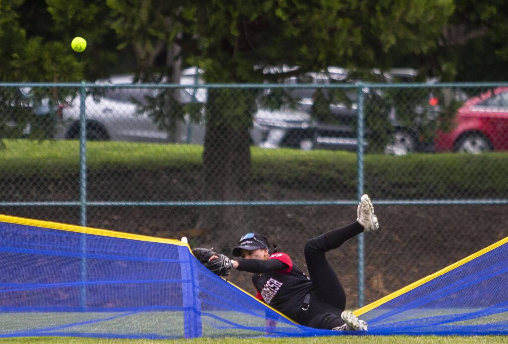 Snohomish’s Audrey Ebia falls over the back fence while trying to catch the ball during the 3A state softball championship game against Auburn Riverside on Saturday, May 25, 2024 in Lacey, Washington. (Olivia Vanni / The Herald)
