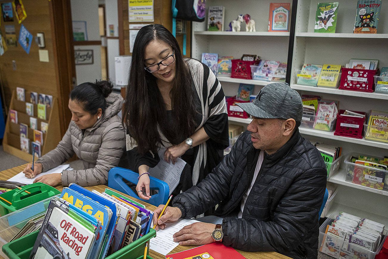 Maricel Samaniego, center, teaches English to Liedith Espana, left, and Nemecio Rios, right, at Liberty Elementary School in Marysville, Washington, on Monday, Jan. 30, 2023. Marysville schools partner with Everett Community College to offer free English classes to parents of multilingual students. (Annie Barker / The Herald)
