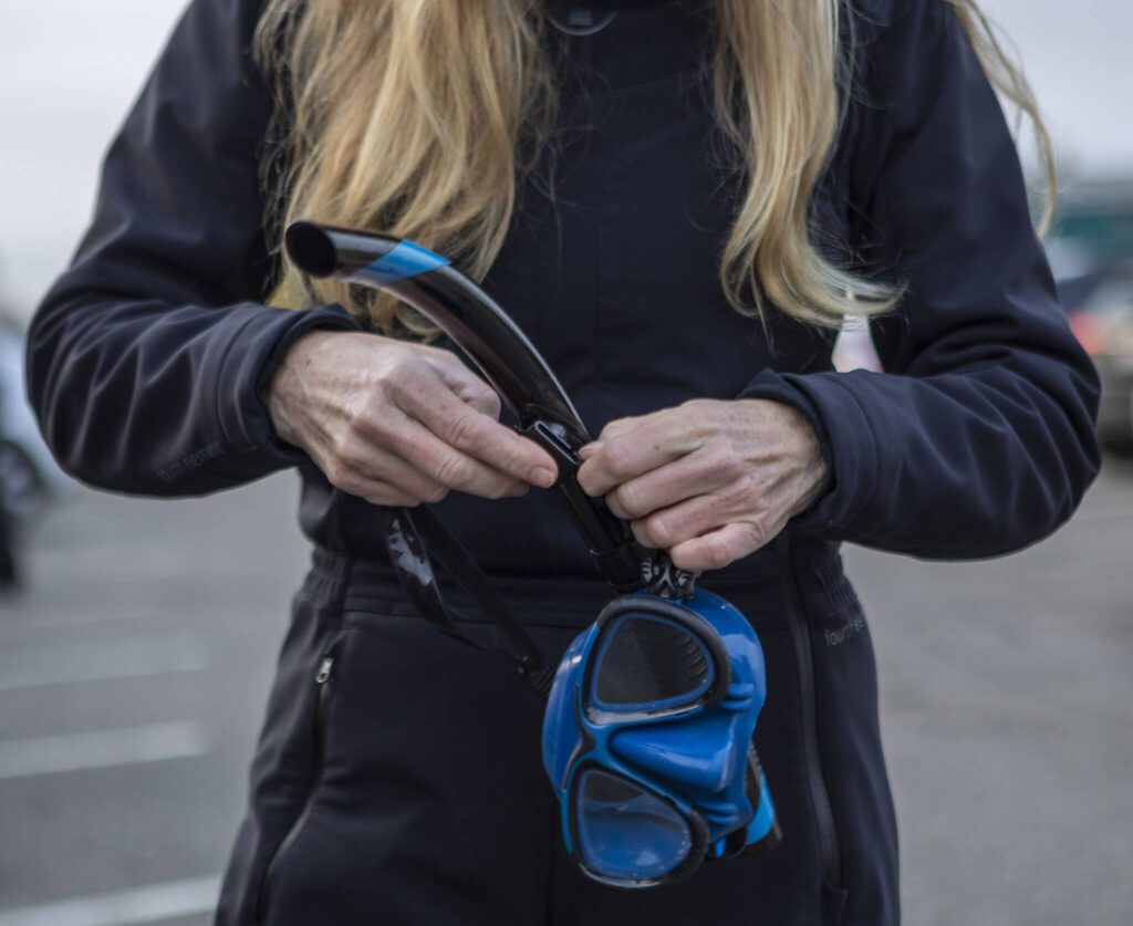 Annie Crawley puts on gear for a portrait at Brackett’s Landing near the Port of Edmonds on Saturday, Feb. 3, 2024 in Edmonds, Washington. (Annie Barker / The Herald)
