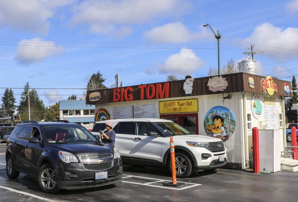 Cars pull up to the Eastside Big Tom drive-thru on March 13 in Olympia, Washington. Big Tom also serves walk-up customers in an outdoor area filled with giant plastic dinosaurs. (Brenda Mann Harrison / Special to The Herald)
