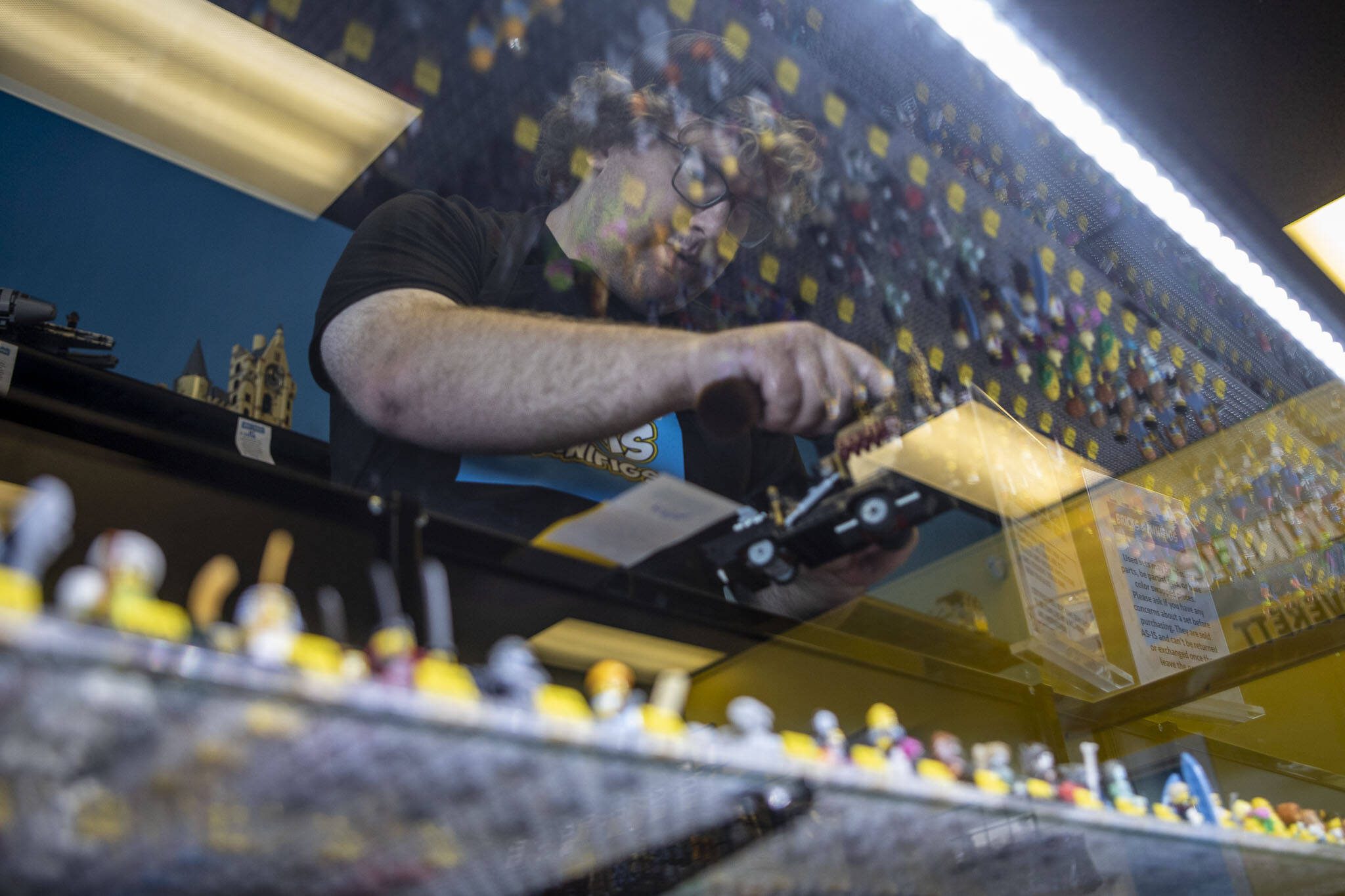 Colt Candland dusts off a hearse above available minifigures at Bricks & Minifigs in Everett, Washington on Thursday, May 30, 2024. (Annie Barker / The Herald)