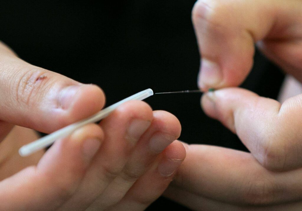 Student Dominick True holds a tiny fiber optic strand during a fiber optic technician training demonstration at Sno-Isle TECH Skills Center on Tuesday, May 28, 2024, in Everett, Washington. (Ryan Berry / The Herald)
