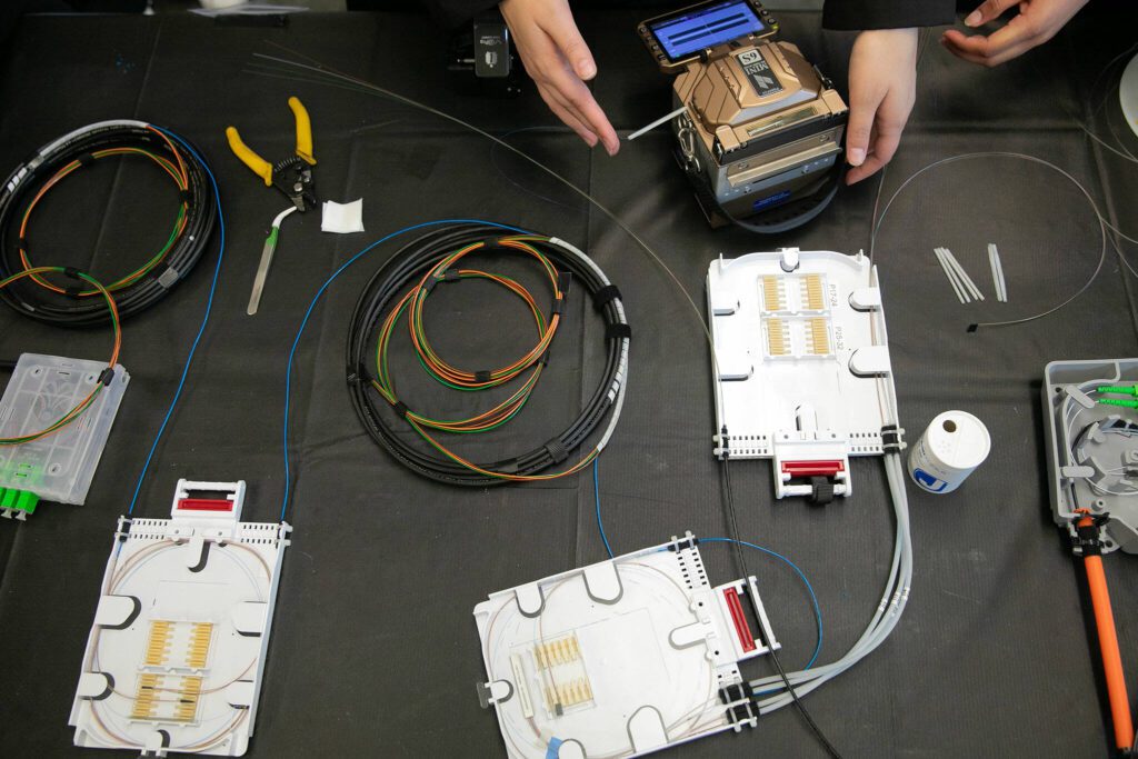 Students work with materials laid out on a table during a fiber optic technician training demonstration at Sno-Isle TECH Skills Center on Tuesday, May 28, 2024, in Everett, Washington. (Ryan Berry / The Herald)
