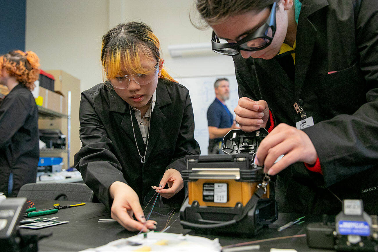 Students Mary Chapman, left, and Nano Portugal, right, work together with a fusion splicer and other equipment during a fiber optic technician training demonstration at Sno-Isle TECH Skills Center on Tuesday, May 28, 2024, in Everett, Washington. (Ryan Berry / The Herald)