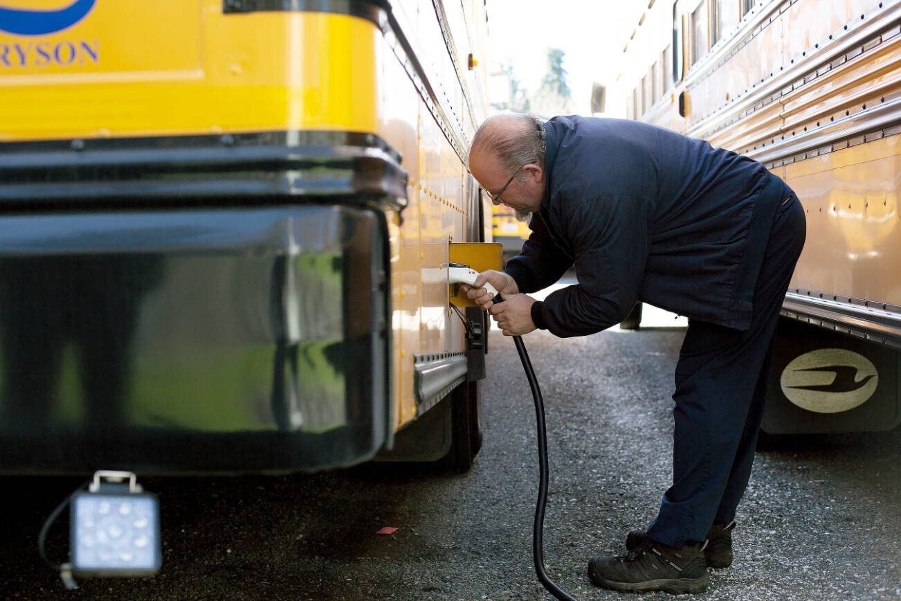 Snohomish School District’s Clayton Lovell plugs in the district’s electric bus after morning routes on Thursday, March 6, 2024, at the district bus depot in Snohomish, Washington. (Ryan Berry / The Herald)