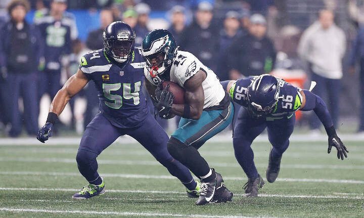 Linebackers Bobby Wagner (54) and Jordyn Brooks (56) close in on Eagles wide receiver A.J. Brown on Dec. 20, 2023, during a game in Philadelphia. (Yong Kim / Philadelphia Inquirer, file)