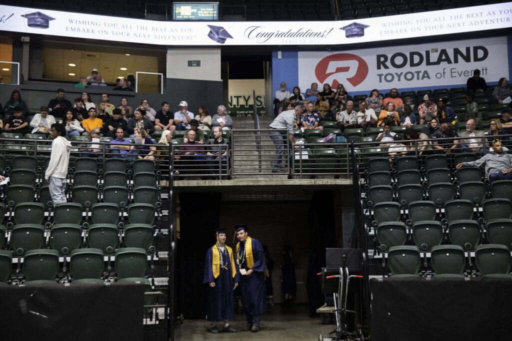 Kobi Spady, left, and Willem Van Dongen look out as people file in before the start of Arlington High School graduation at Angel of the Winds Arena on Thursday, June 13, 2024, in Everett, Washington. (Olivia Vanni / The Herald)

