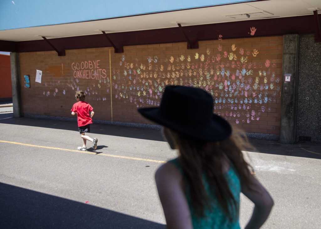 Children run past a wall of chalk handprints while saying goodbye to their school on Tuesday, June 25, 2024, in Lynnwood, Washington. (Olivia Vanni / The Herald)
