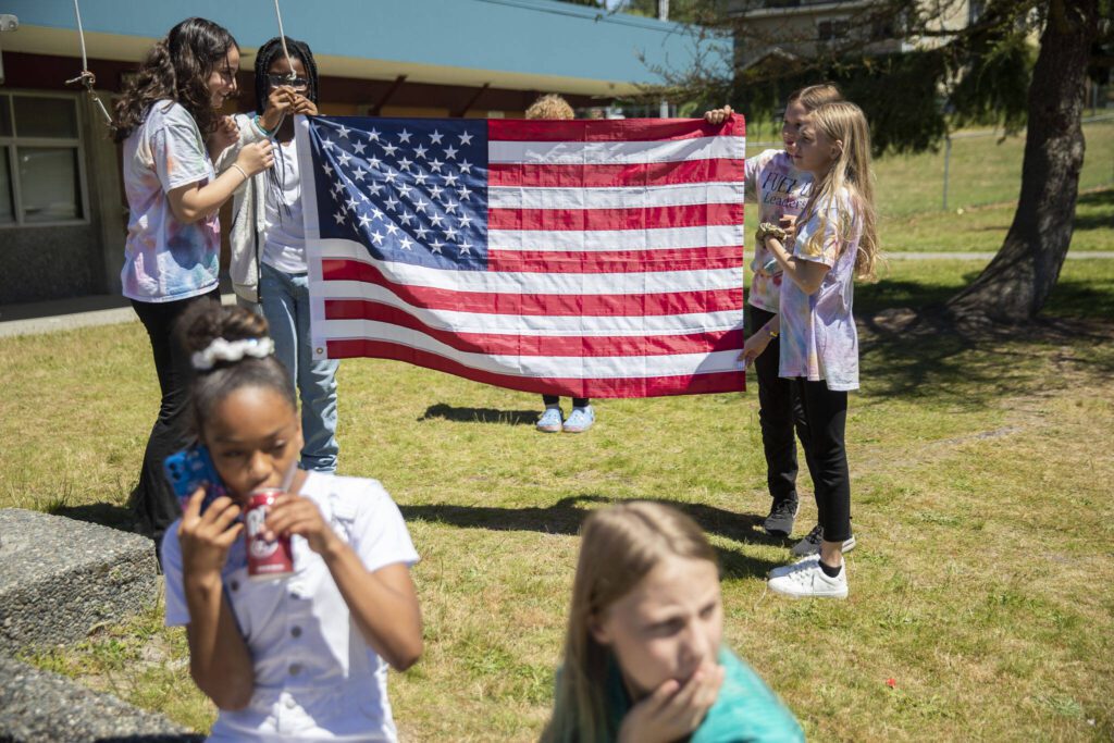 Oak Heights Elementary students lower the flag before the start of the groundbreaking on Tuesday, June 25, 2024 in Lynnwood, Washington. (Olivia Vanni / The Herald)
