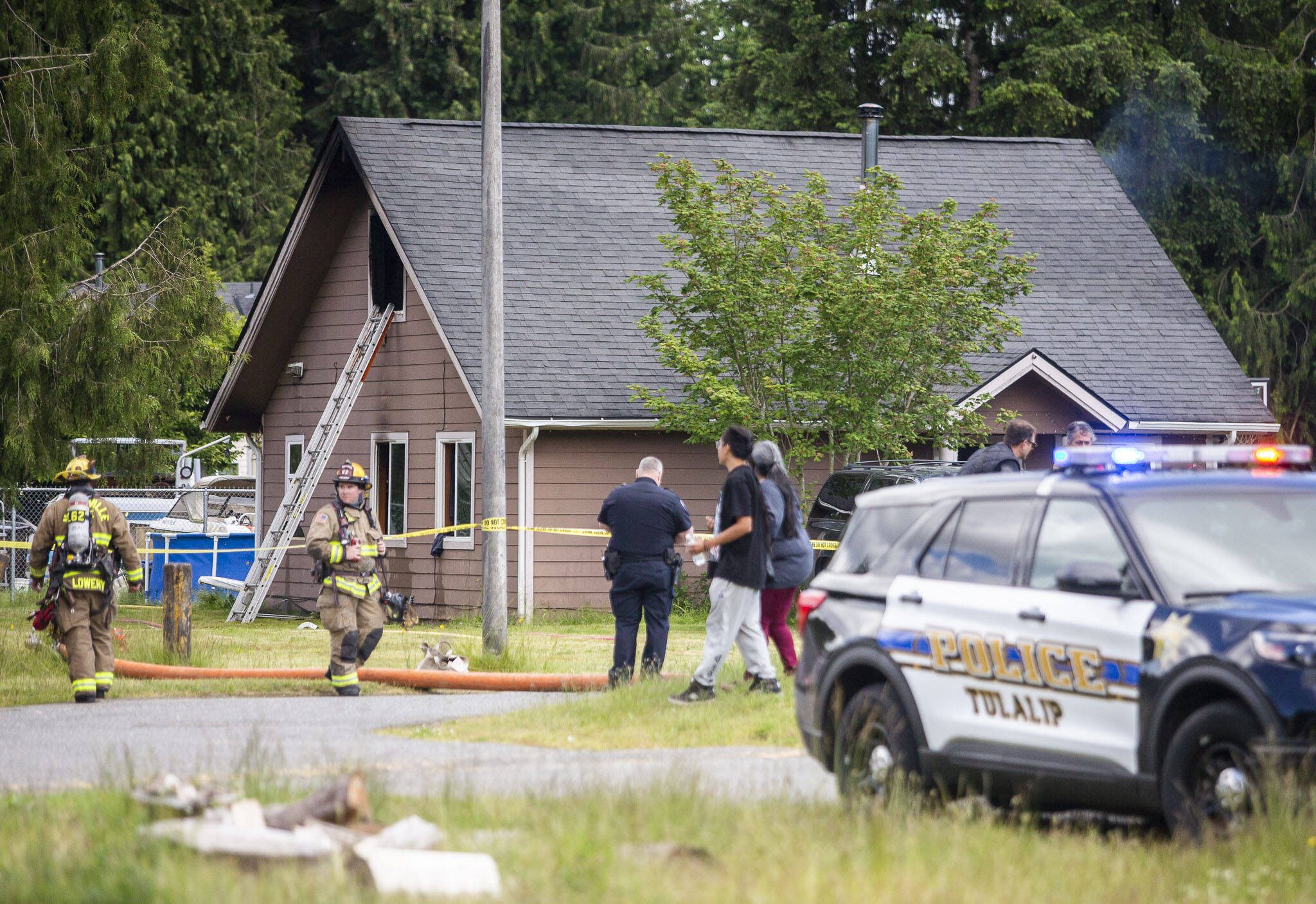 Firefighters and police walk around a home that caught fire on Tuesday, June 18, 2024 in Tulalip, Washington. (Olivia Vanni / The Herald)