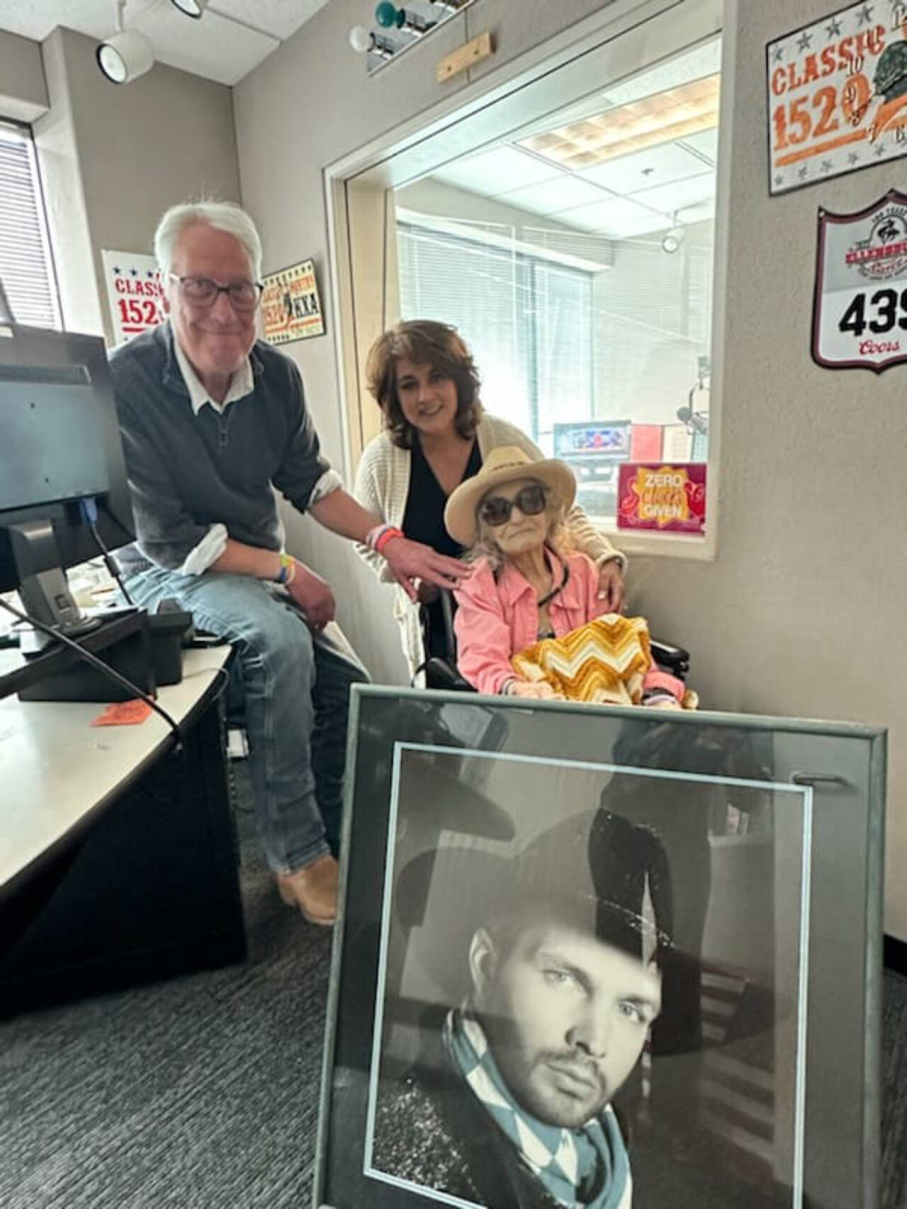 Charlye Parker poses with a framed photo of Garth Brooks and KXA radio personalities Stitch Mitchell and Anita Moffett. (Provided photo)