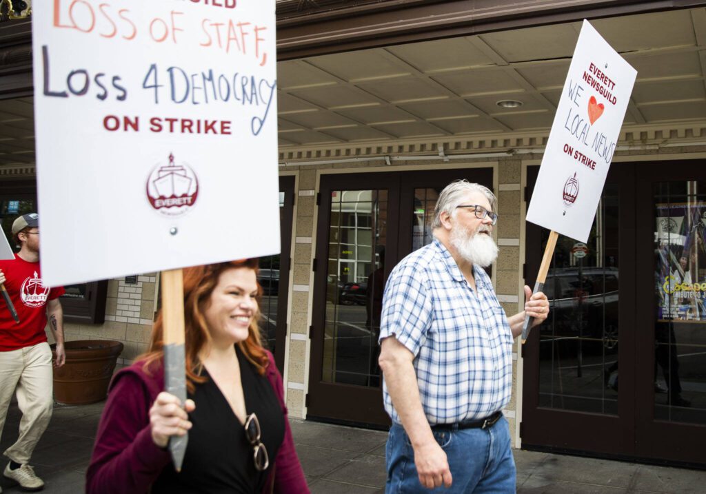Jon Bauer, right, the opinion page editor at the Herald, holds a sign and walks down Colby Avenue during the Everett NewsGuild strike on Monday, June 24, 2024, in Everett, Washington. (Olivia Vanni / The Herald)
