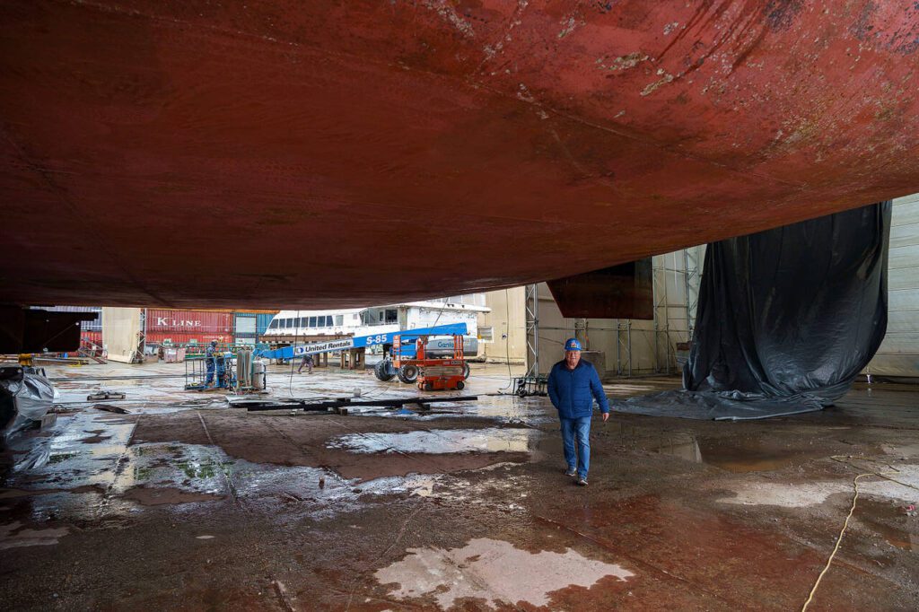 Matt Nichols walks beneath the giant hull of a boat during an event at the Freeland boat company years ago. (Photo by David Welton)
