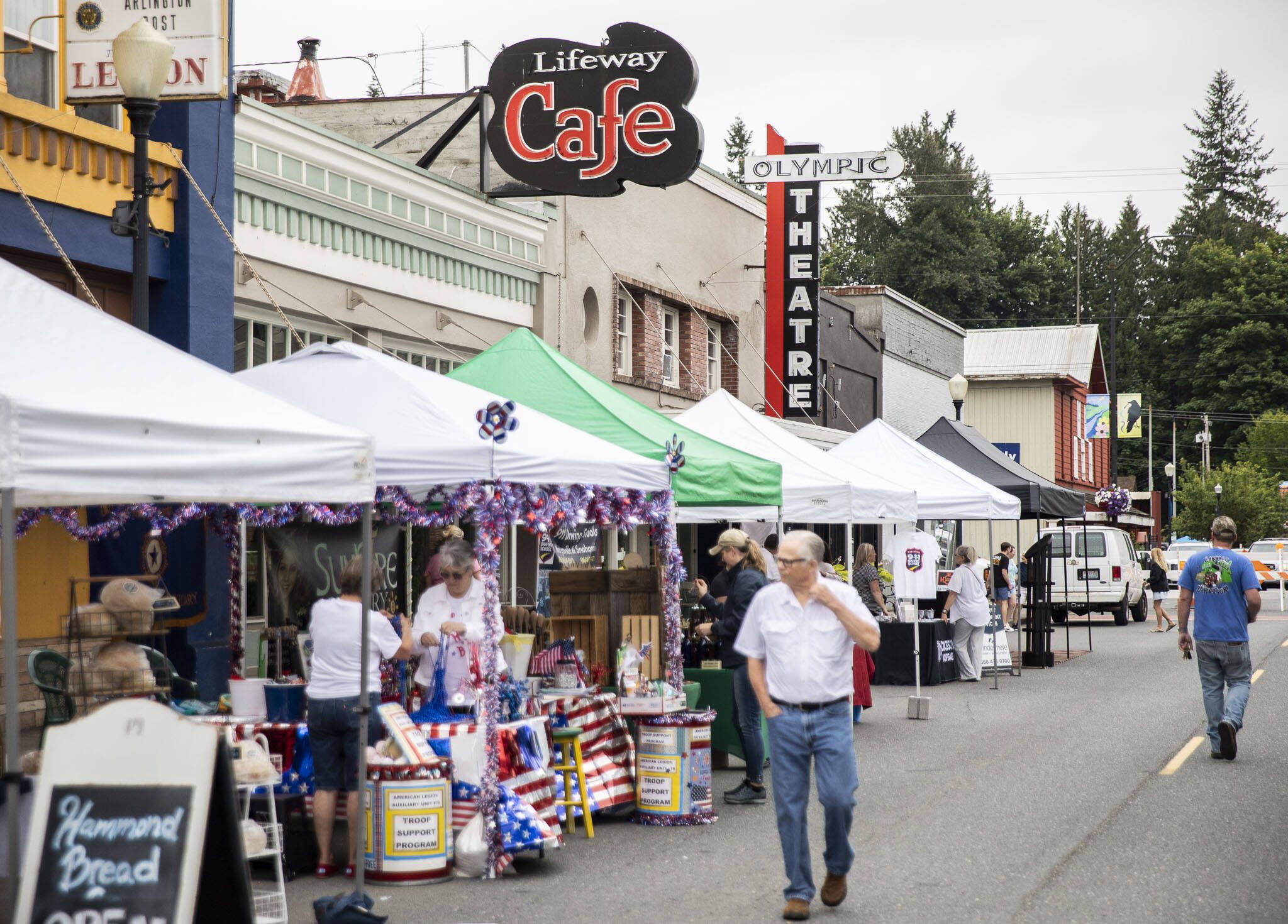 People walk along Olympic Avenue past Lifeway Cafe and Olympic Theater that currently hosts Lifeway Church on Friday, July 7, 2023, in Arlington, Washington. (Olivia Vanni / The Herald)