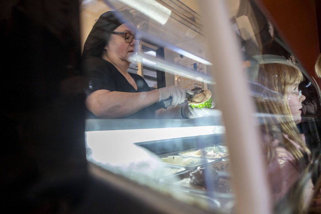 Mona Newbauer scoops gelato while a child watches inside her store Sweet Mona’s Chocolates. (Annie Barker / The Herald)
