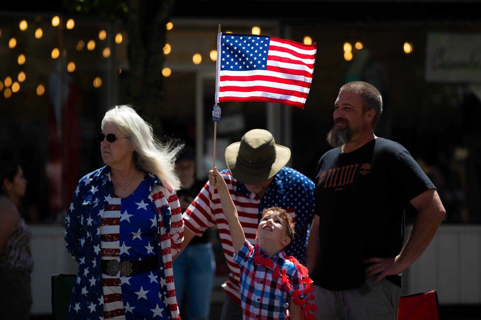 A young child holds up an American Flag during Everett’s Fourth of July Parade on Thursday, July 4, 2024, in downtown Everett, Washington. (Ryan Berry / The Herald)