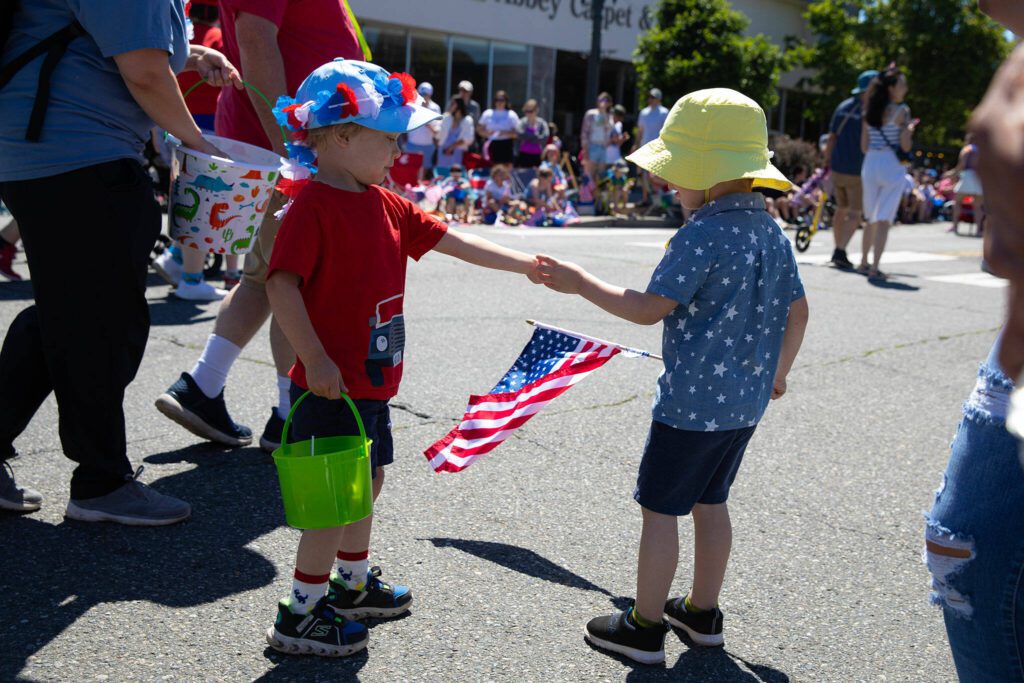 Two children exchange candy during Everett’s Fourth of July Parade on Thursday, July 4, 2024, in downtown Everett, Washington. (Ryan Berry / The Herald)
