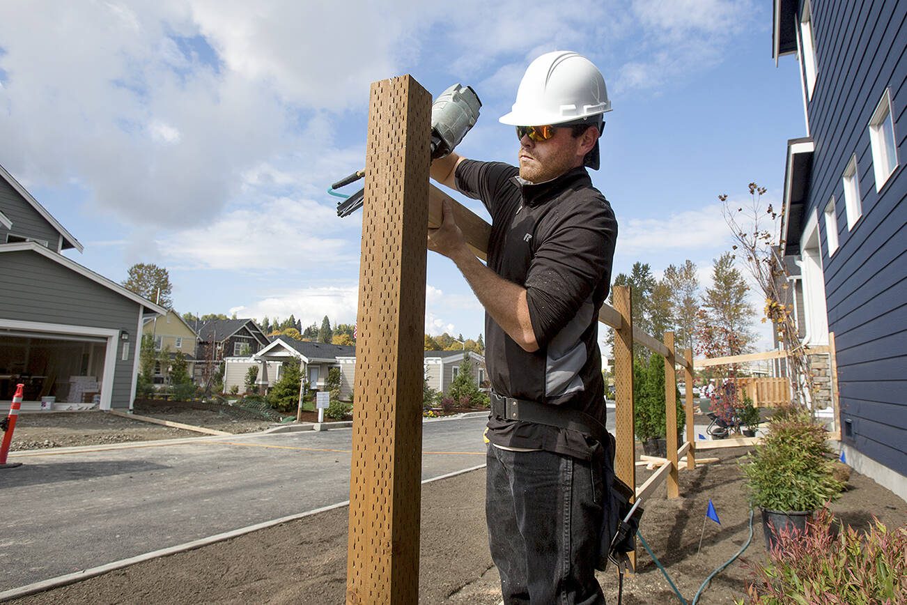 Matthew Wallace, of D&L Fence, Inc., nails in a fence support on a model home at the Overlook at Riverfront on Monday, Oct. 10, 2016 in Everett, Wa. The project by Polygon Northwest has the first 30 homes, of 425 planned along the riverfront, in various stages of construction. (Andy Bronson / The Herald)