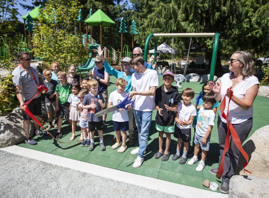 Family, friends and neighbors of Jim Corcoran help cut the ribbon to signify the opening of the Corcoran Memorial Park on Friday in Bothell, Washington. (Olivia Vanni / The Herald)

