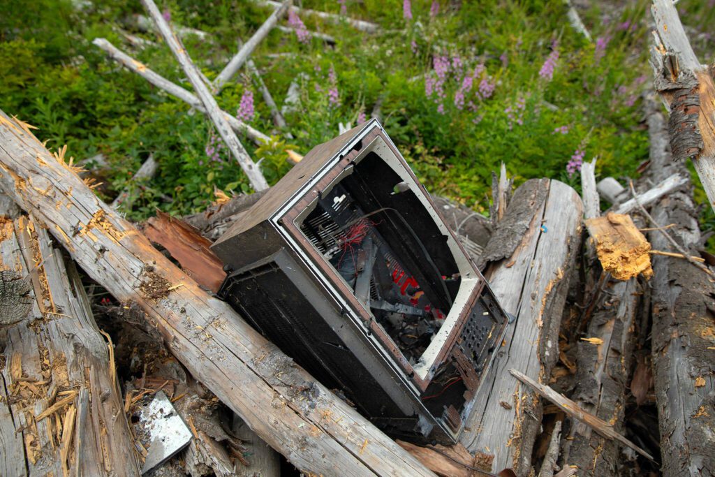 An old television tops a pile of trash and debris where other items such as a laptop, coffee canisters and even a LEGO set can be found riddled with bullet holes at a shooting area on Green Mountain Road on Wednesday, July 17, 2024, near Granite Falls, Washington. (Ryan Berry / The Herald)
