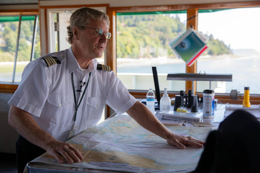 Captain Russell Fee pulls out a map to talk about navigating Puget Sound while aboard the MV Spokane on the Edmonds/Kingston ferry route Thursday, July 18, 2024, near Edmonds, Washington. The longtime practice of using paper maps will end in August, as the ferry system will have all maps digitally available to crew. (Ryan Berry / The Herald)

