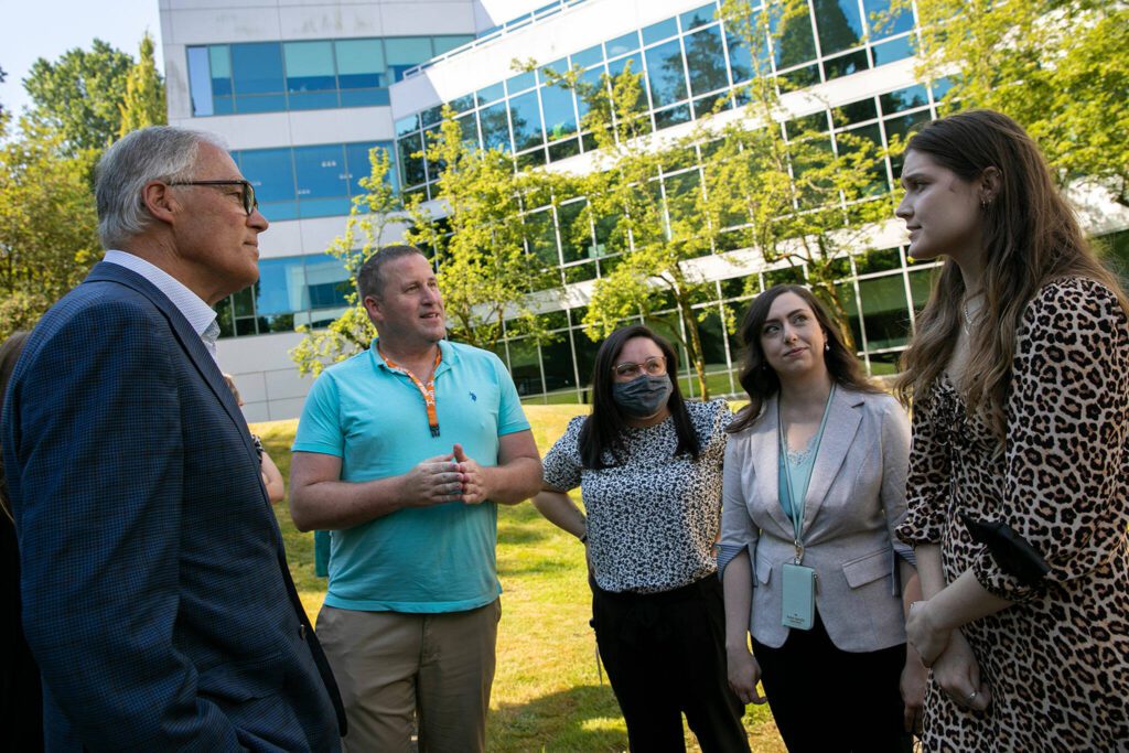 A group of Volunteers of America crisis counselors and workers meet with Gov. Jay Inslee, left, after the governor toured their facility and gave a brief address about mental health services on Thursday, July 28, 2022, outside the VOA Behavioral Health Crisis Call Center in Everett, Washington. (Ryan Berry / The Herald)
